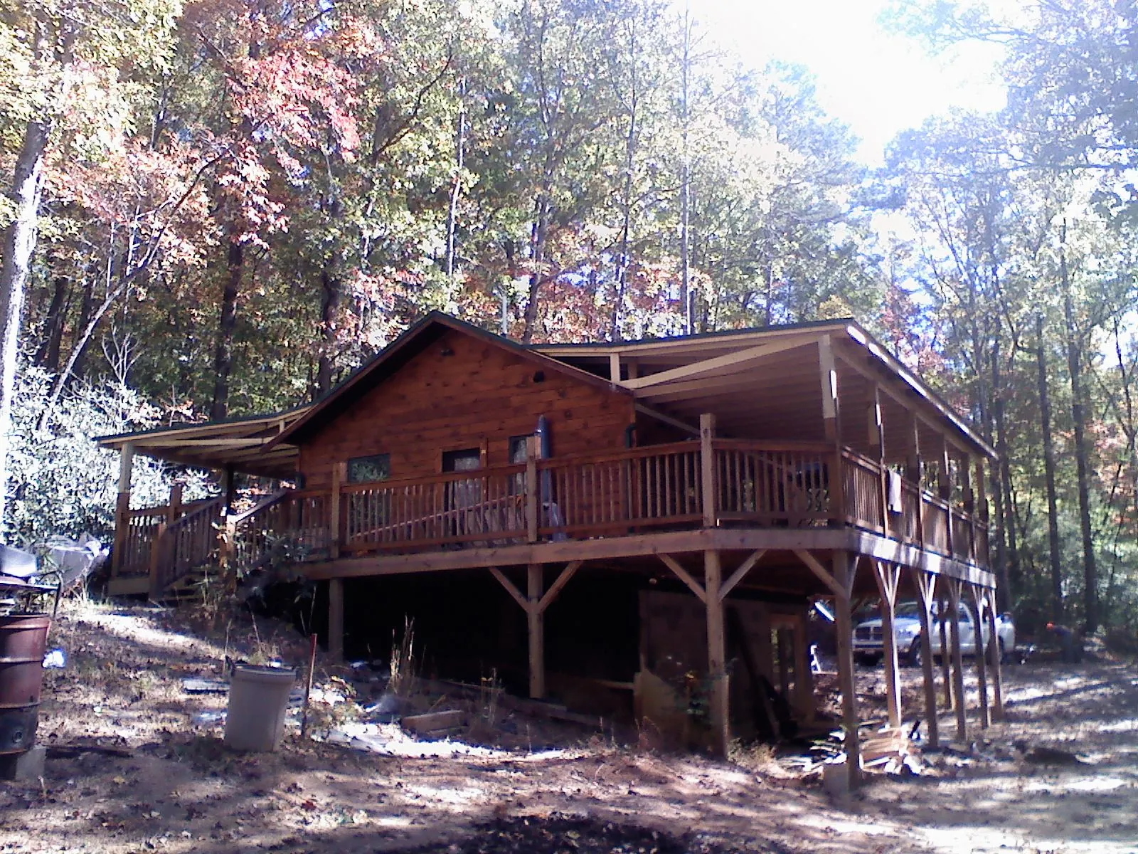 Log cabin with a wraparound porch and metal roof in the fall in Willis