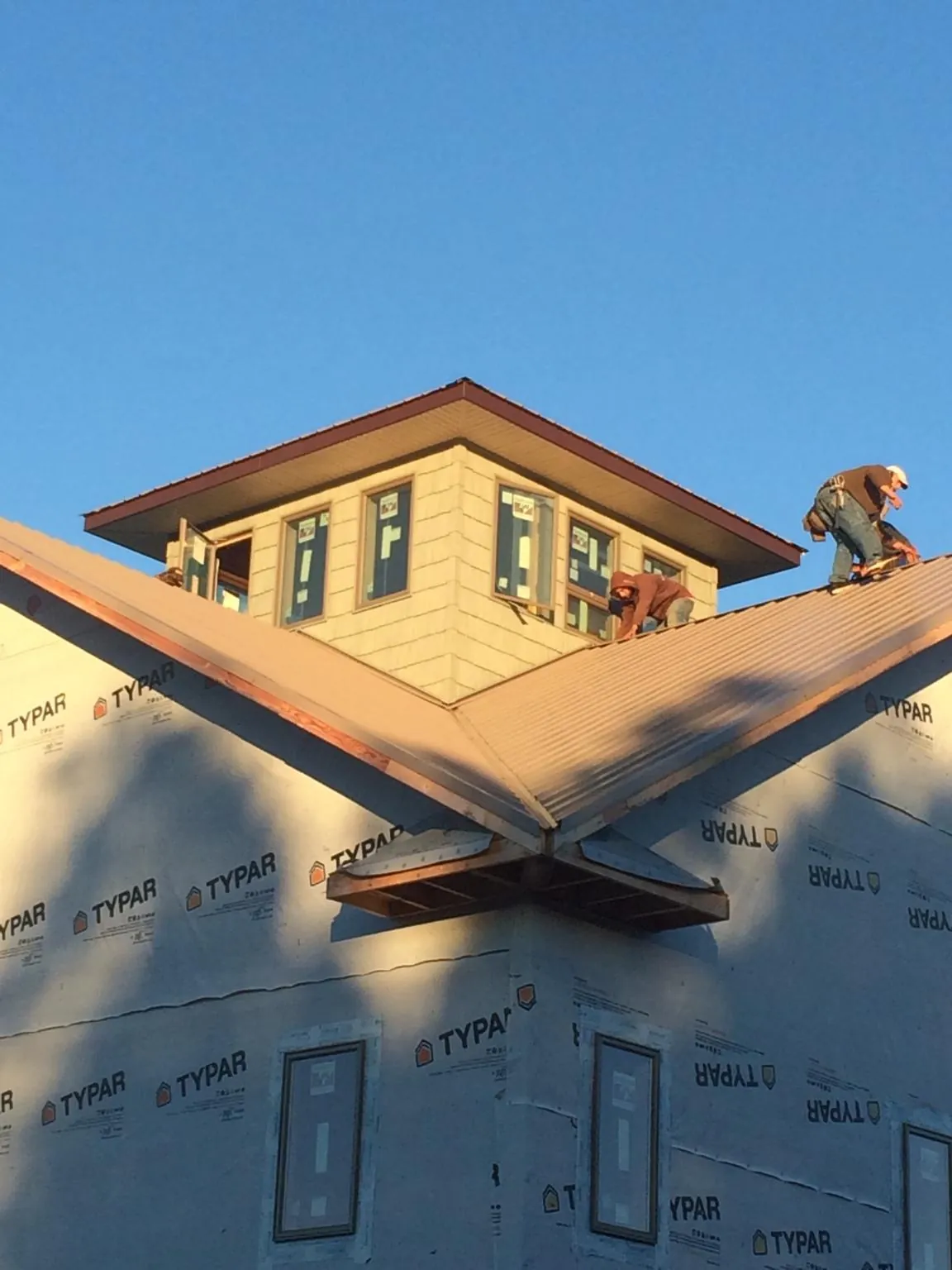 Roofers working around a rooftop cupola on a new metal roof at sunset — Roof Waterproofing in Willis by Roofing Brothers